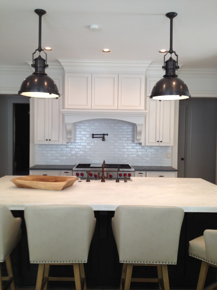 Example of a country light wood floor kitchen design in Atlanta with a farmhouse sink, shaker cabinets, white cabinets, granite countertops, white backsplash, ceramic backsplash, stainless steel appliances and an island