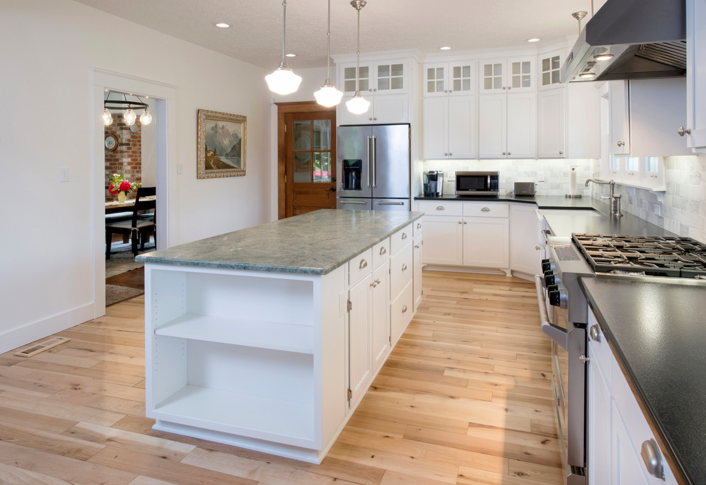 Inspiration for a mid-sized cottage l-shaped light wood floor and brown floor eat-in kitchen remodel in Portland with a farmhouse sink, shaker cabinets, white cabinets, granite countertops, multicolored backsplash, marble backsplash, stainless steel appliances, an island and green countertops