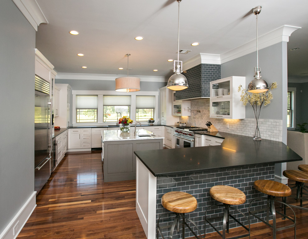 Eat-in kitchen - mid-sized modern u-shaped medium tone wood floor eat-in kitchen idea in Dallas with an undermount sink, shaker cabinets, white cabinets, marble countertops, gray backsplash, stone tile backsplash and stainless steel appliances