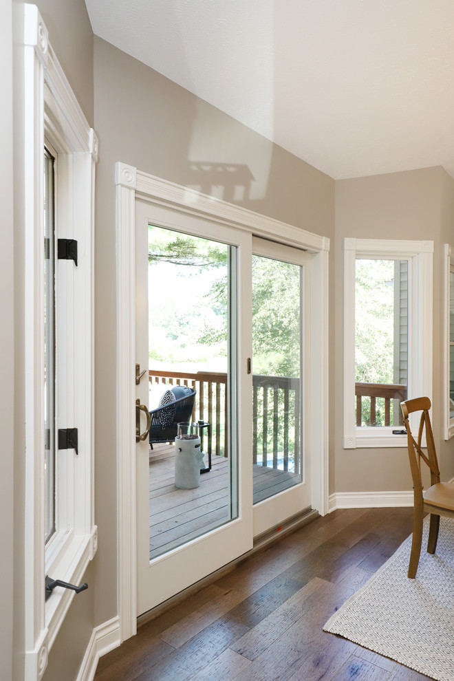 Example of a mid-sized farmhouse l-shaped light wood floor and brown floor eat-in kitchen design in Grand Rapids with a farmhouse sink, shaker cabinets, white cabinets, quartz countertops, gray backsplash, ceramic backsplash, stainless steel appliances and an island