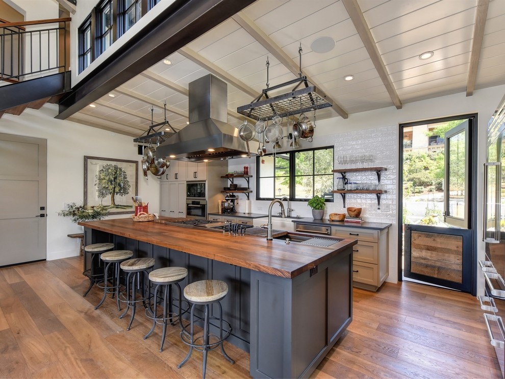 Klassische Küchenbar mit Landhausspüle, Schrankfronten im Shaker-Stil, grauen Schränken, Arbeitsplatte aus Holz, Küchenrückwand in Weiß, braunem Holzboden und Kücheninsel in Sacramento