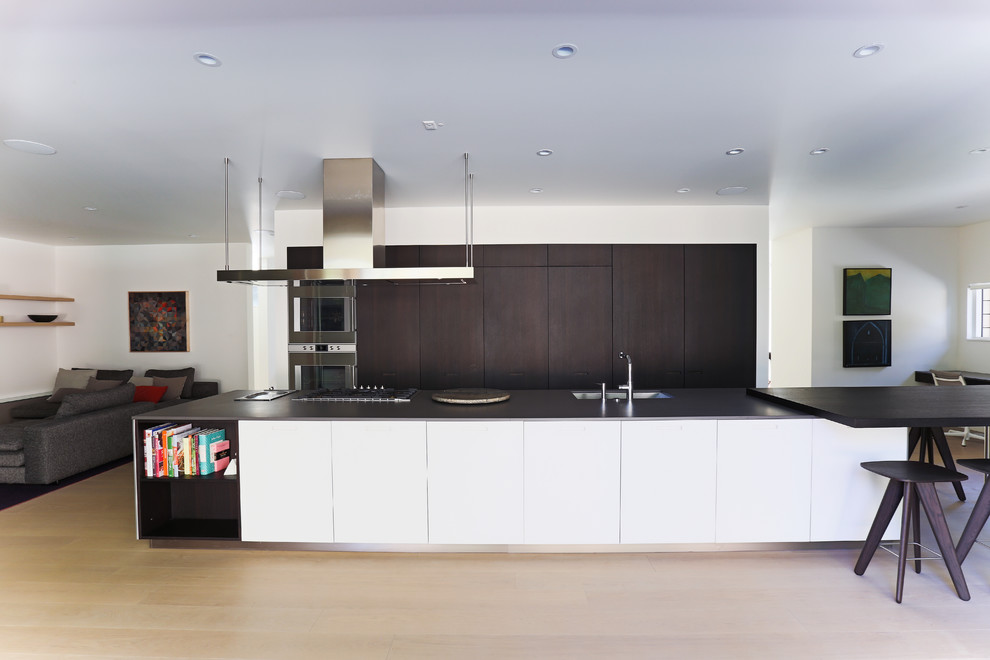 Imagen de cocina lineal minimalista con armarios con paneles lisos, puertas de armario de madera en tonos medios, suelo de madera clara y una isla