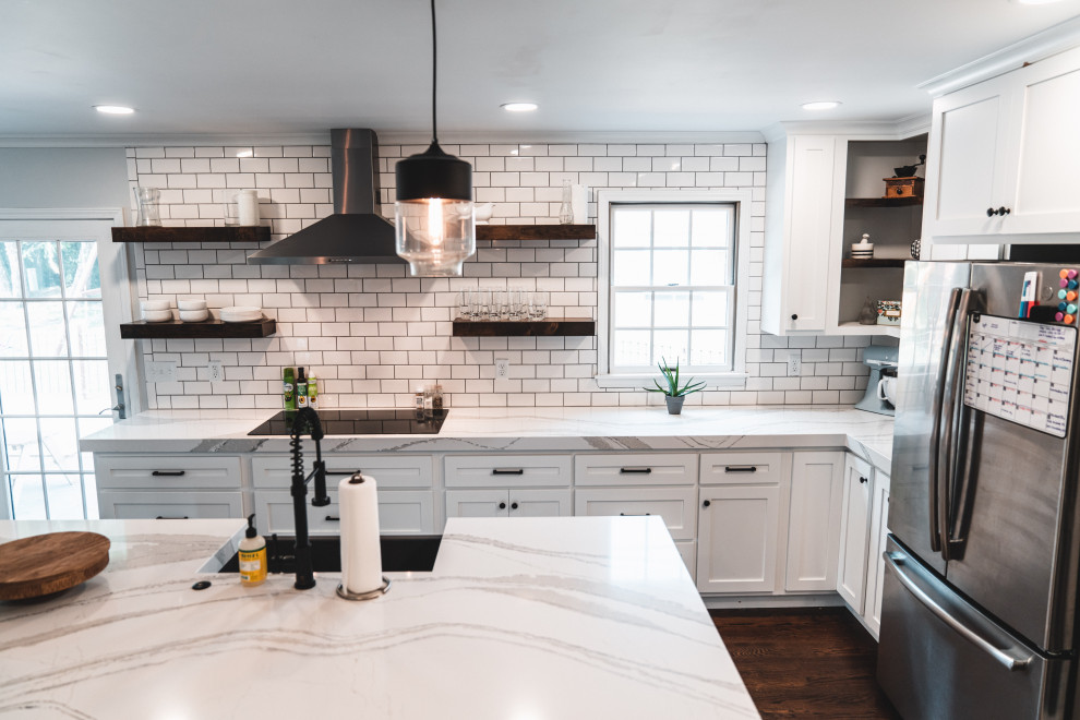 Example of a large country l-shaped dark wood floor and brown floor eat-in kitchen design in Other with a farmhouse sink, shaker cabinets, white cabinets, quartz countertops, white backsplash, subway tile backsplash, stainless steel appliances, an island and white countertops