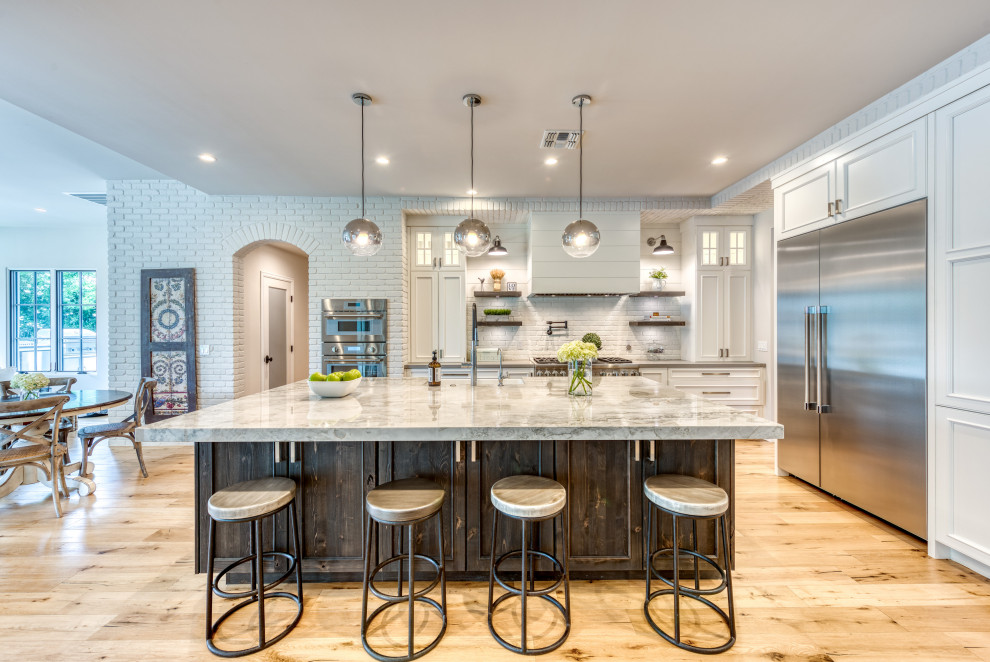 Country u-shaped medium tone wood floor and brown floor eat-in kitchen photo in Phoenix with a farmhouse sink, recessed-panel cabinets, white cabinets, white backsplash, subway tile backsplash, an island and multicolored countertops