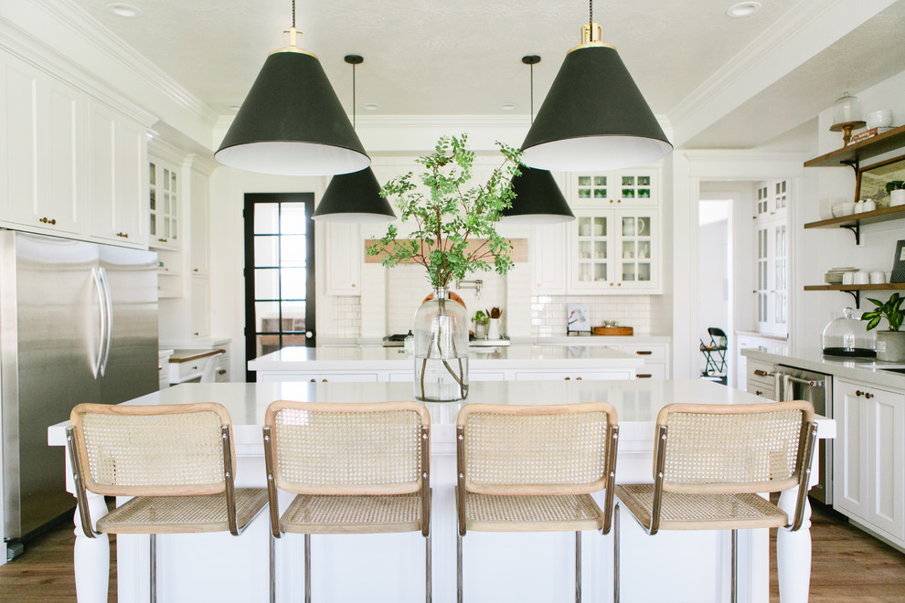 Landhaus Küche in U-Form mit Glasfronten, Küchenrückwand in Weiß, Rückwand aus Metrofliesen, Küchengeräten aus Edelstahl, braunem Holzboden und zwei Kücheninseln in Salt Lake City