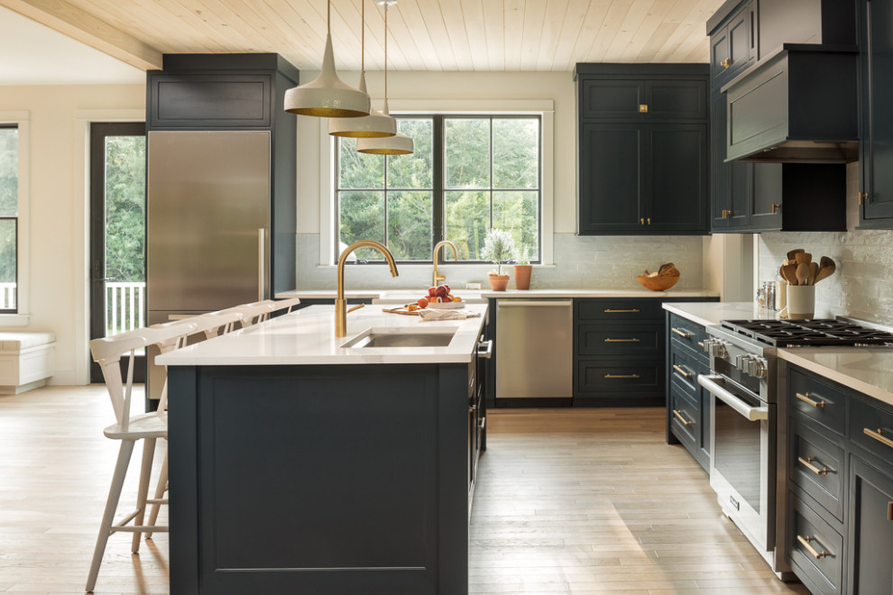 Inspiration for a large country l-shaped kitchen in Portland Maine with a submerged sink, shaker cabinets, grey cabinets, white splashback, glass tiled splashback, stainless steel appliances, light hardwood flooring, an island, beige floors and white worktops.