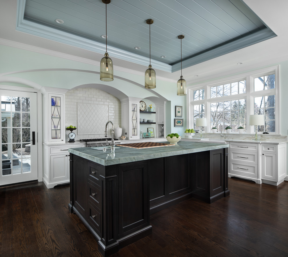 Inspiration for a large timeless l-shaped dark wood floor and brown floor enclosed kitchen remodel in Detroit with a farmhouse sink, white cabinets, marble countertops, white backsplash, stainless steel appliances, an island, white countertops, shaker cabinets and subway tile backsplash