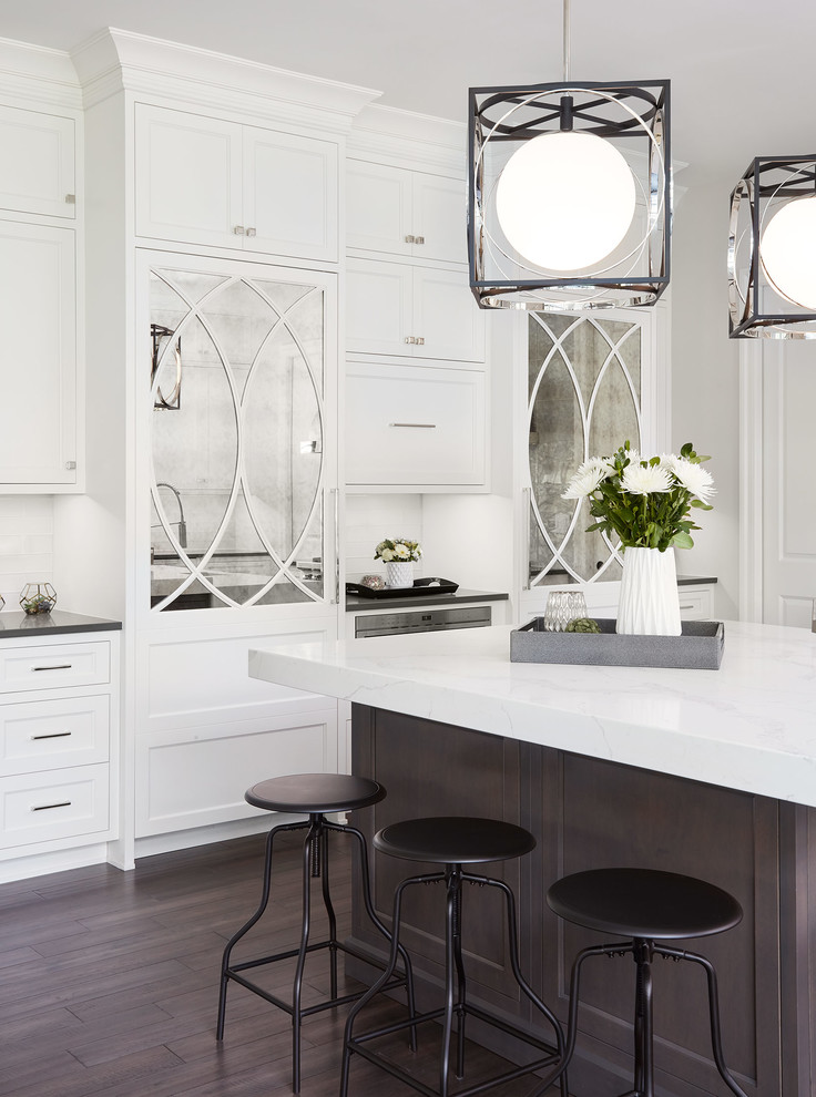 Traditional l-shaped kitchen/diner in Chicago with a belfast sink, shaker cabinets, white cabinets, grey splashback, metro tiled splashback, stainless steel appliances, dark hardwood flooring and an island.