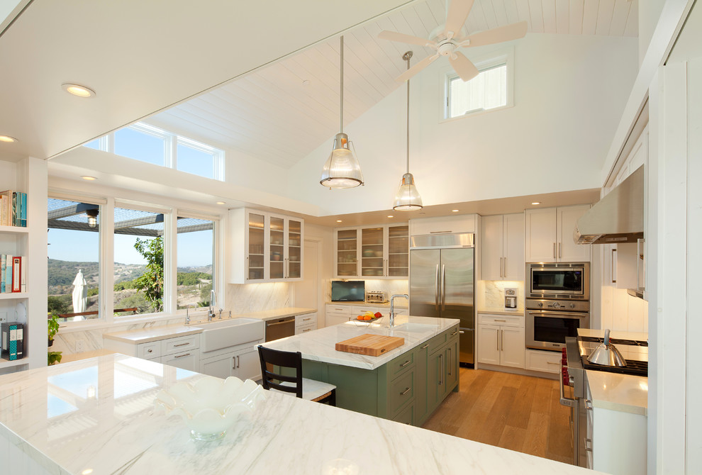 Inspiration for a farmhouse u-shaped kitchen remodel in San Luis Obispo with a farmhouse sink, recessed-panel cabinets, white cabinets, white backsplash and stainless steel appliances