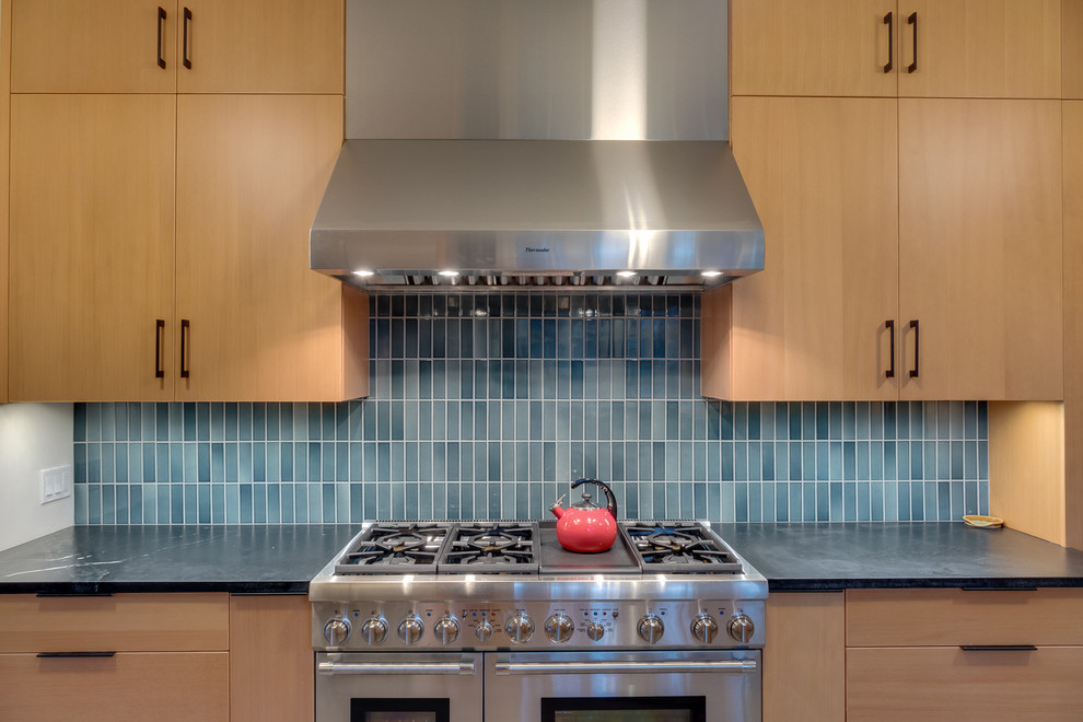 Foto på ett mellanstort funkis kök, med en rustik diskho, släta luckor, skåp i ljust trä, bänkskiva i kvartsit, blått stänkskydd, stänkskydd i glaskakel, rostfria vitvaror och mellanmörkt trägolv