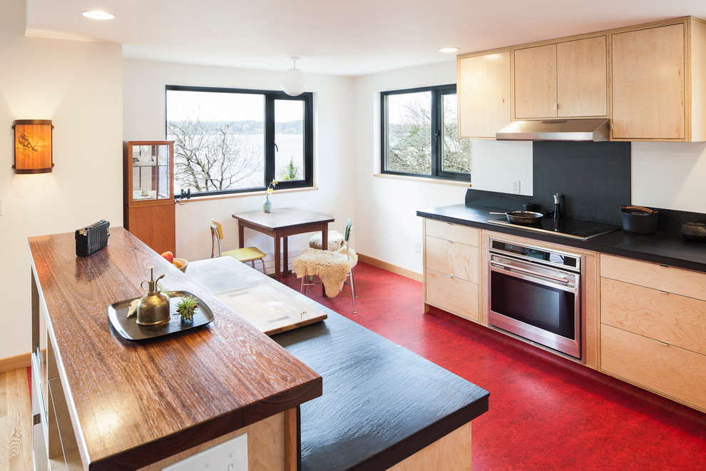 Photo of a modern kitchen in Seattle with wood worktops and red floors.