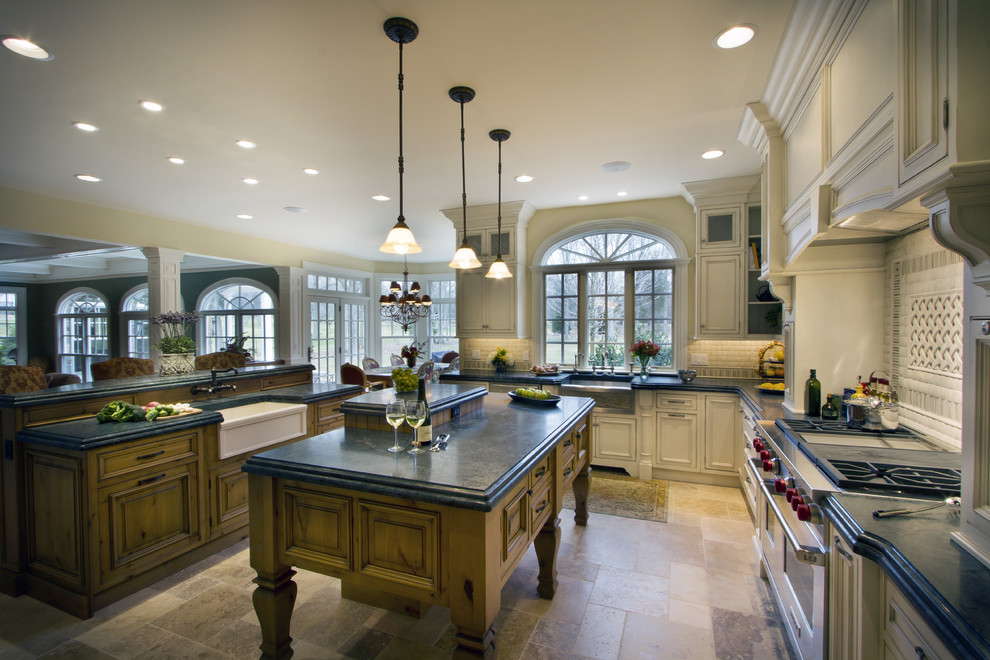 Inspiration for a french country travertine floor eat-in kitchen remodel in New York with a farmhouse sink, recessed-panel cabinets, medium tone wood cabinets, marble countertops, white backsplash, mosaic tile backsplash, stainless steel appliances and an island