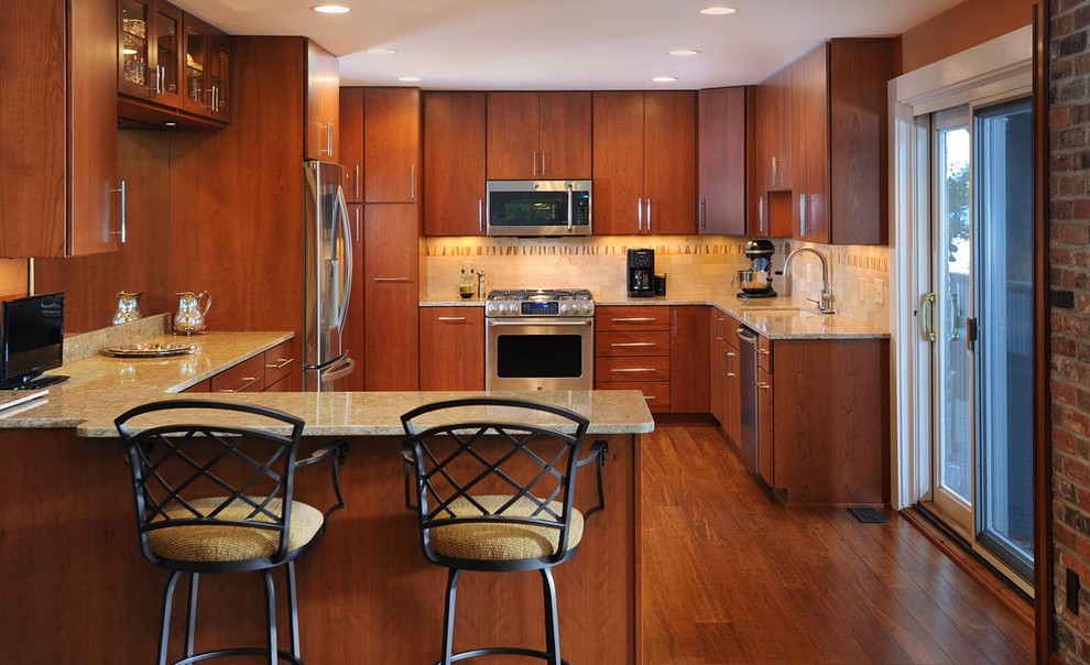 Moderne Wohnküche in U-Form mit Unterbauwaschbecken, hellbraunen Holzschränken, Granit-Arbeitsplatte, Küchengeräten aus Edelstahl, braunem Holzboden und Halbinsel in Nashville
