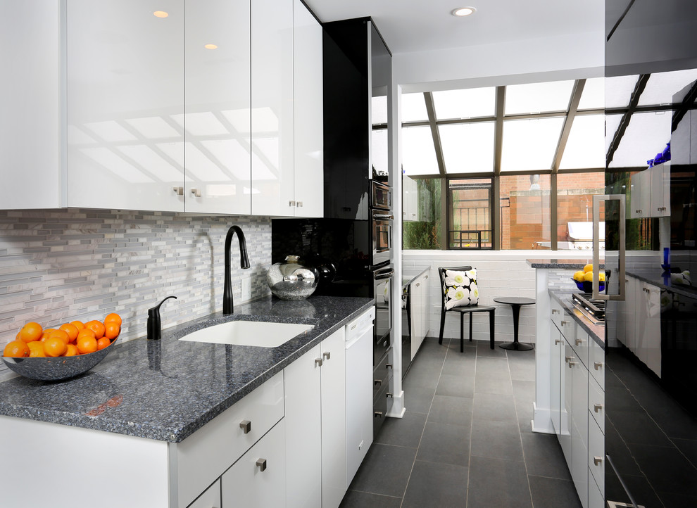 Photo of a small contemporary galley enclosed kitchen in Chicago with a submerged sink, flat-panel cabinets, grey splashback, matchstick tiled splashback, black appliances, no island, engineered stone countertops and porcelain flooring.