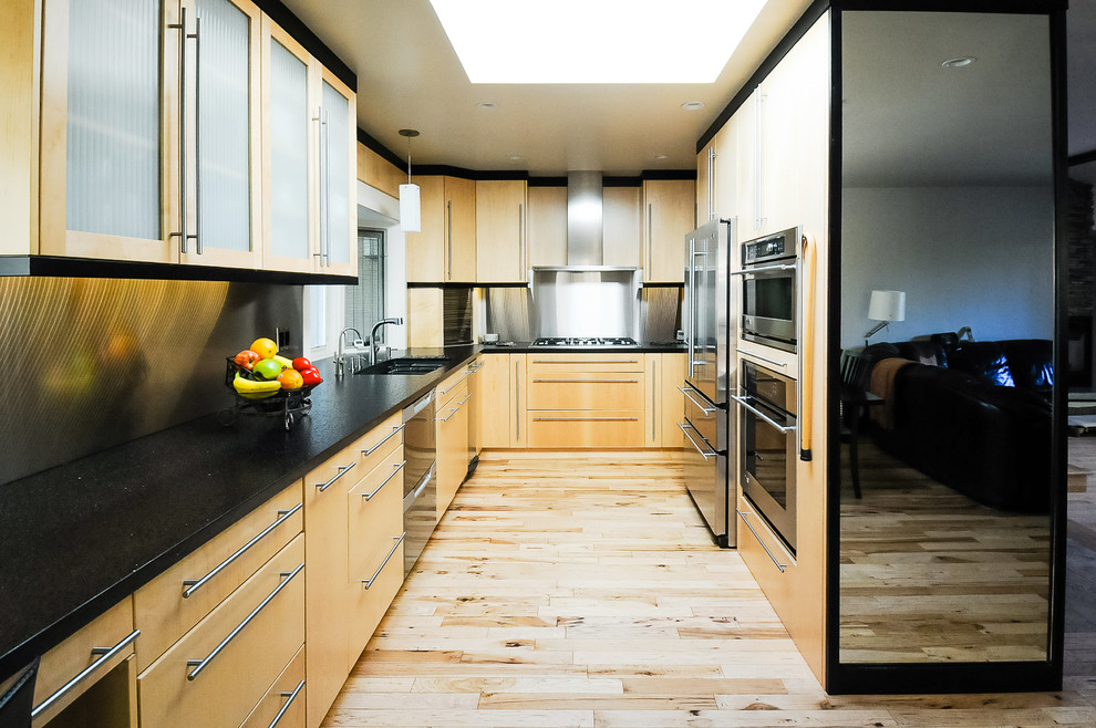Idee per una cucina design di medie dimensioni con ante lisce, ante in legno chiaro, elettrodomestici in acciaio inossidabile e parquet chiaro