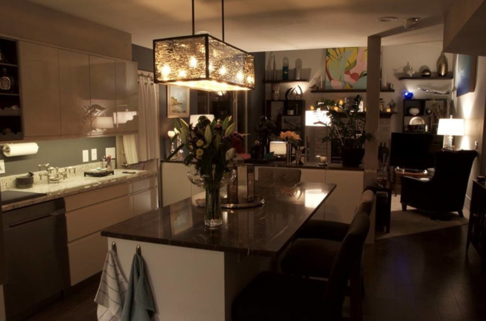Cette image montre une cuisine américaine minimaliste en L de taille moyenne avec un placard à porte plane, des portes de placard beiges, un plan de travail en granite, une crédence beige, îlot et un plan de travail gris.