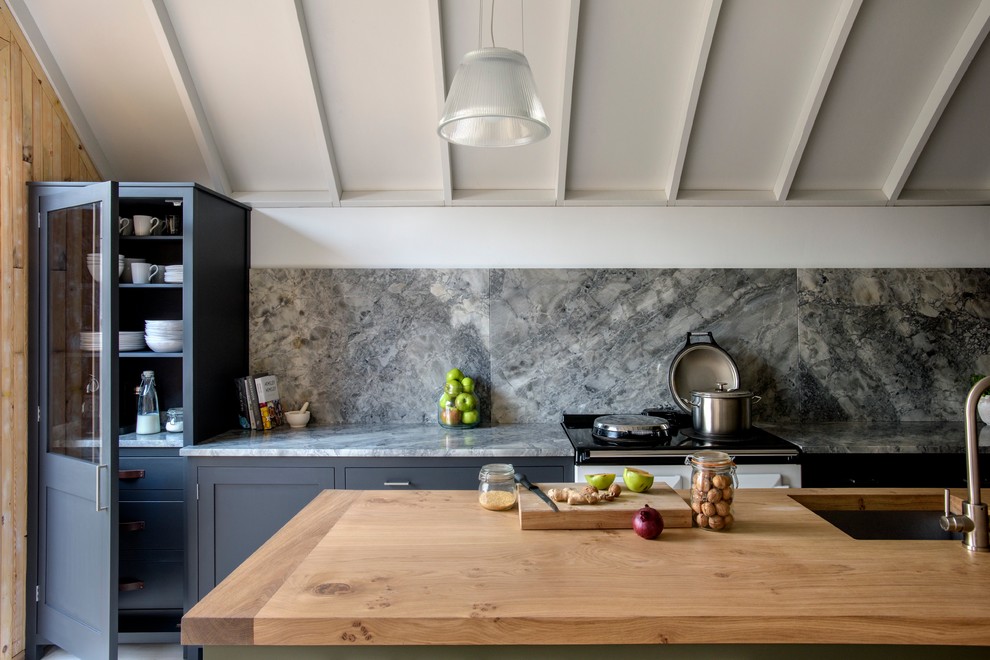 Idee per un cucina con isola centrale country con lavello sottopiano, ante di vetro, top in legno e paraspruzzi grigio