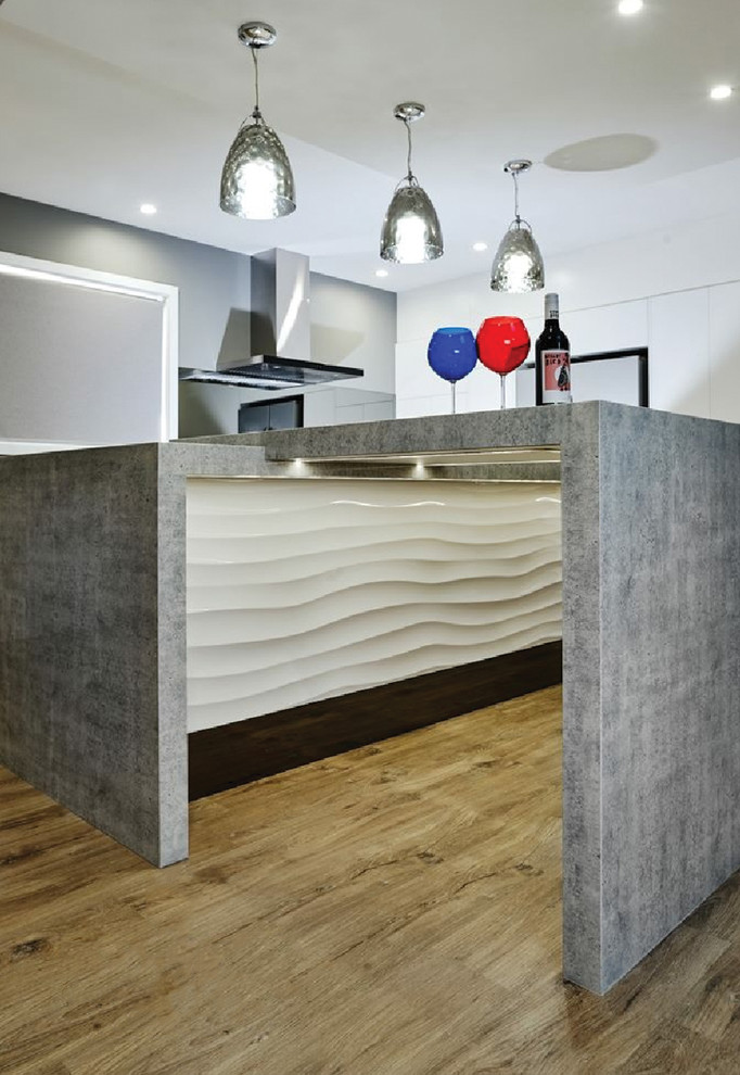Example of a large minimalist medium tone wood floor and beige floor kitchen design in Miami with white cabinets, terrazzo countertops, gray backsplash, an island and gray countertops