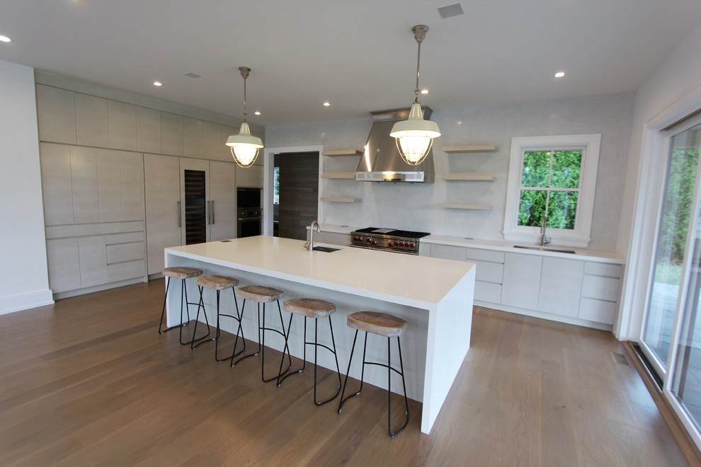 Huge minimalist u-shaped medium tone wood floor and brown floor eat-in kitchen photo in New York with an undermount sink, flat-panel cabinets, white cabinets, stainless steel appliances and an island