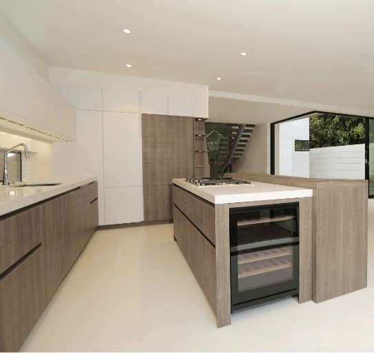 Foto de cocinas en L minimalista con armarios con paneles lisos, puertas de armario de madera clara, electrodomésticos de acero inoxidable y una isla
