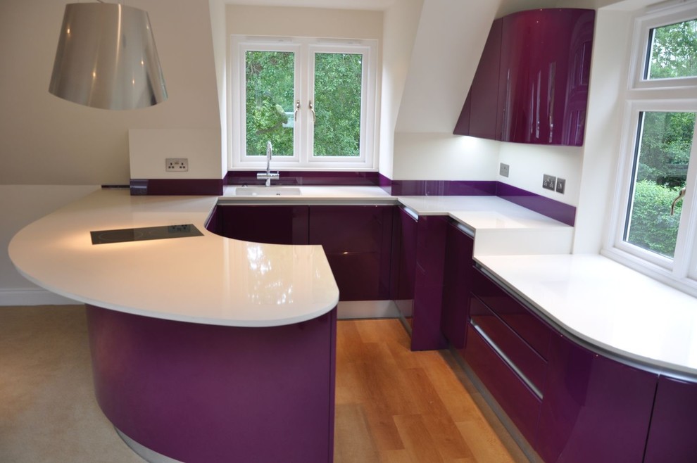 Mid-sized trendy u-shaped light wood floor and brown floor open concept kitchen photo in Kent with a drop-in sink, flat-panel cabinets, purple cabinets, quartzite countertops, glass sheet backsplash, black appliances, a peninsula and white countertops