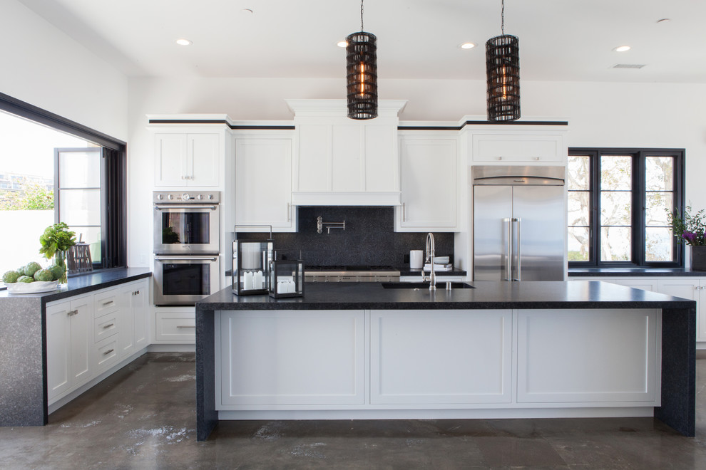 Inspiration for a mid-sized transitional l-shaped concrete floor open concept kitchen remodel in Orange County with an undermount sink, shaker cabinets, black backsplash, glass tile backsplash, stainless steel appliances, an island and black countertops