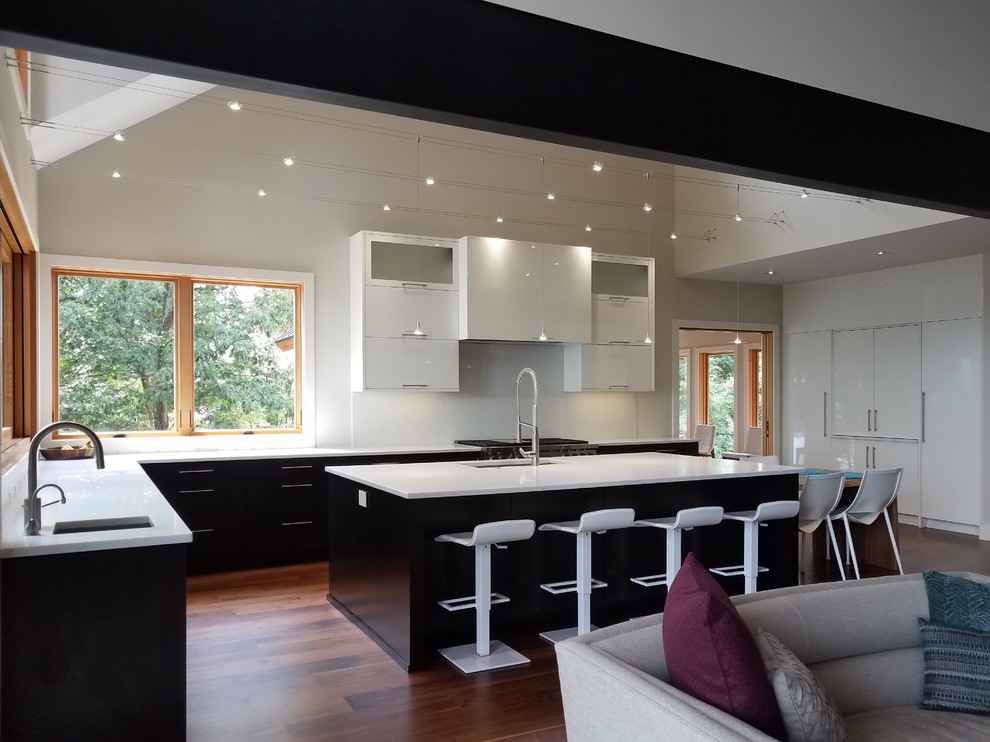 Photo of a large modern u-shaped kitchen/diner in Other with a submerged sink, flat-panel cabinets, dark wood cabinets, engineered stone countertops, white splashback, stainless steel appliances, dark hardwood flooring, an island, brown floors and white worktops.