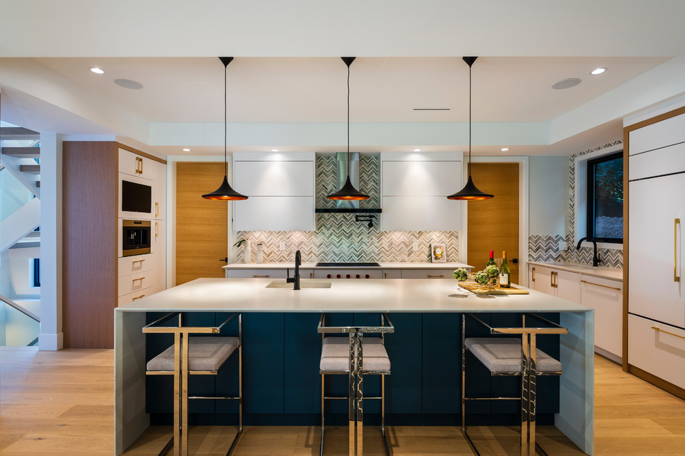 Example of a mid-sized trendy u-shaped medium tone wood floor and brown floor open concept kitchen design in Vancouver with an undermount sink, flat-panel cabinets, white cabinets, quartz countertops, gray backsplash, marble backsplash, paneled appliances, an island and white countertops
