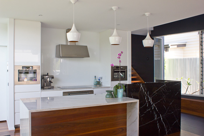 Esempio di un grande cucina con isola centrale minimalista con ante bianche, top in marmo, paraspruzzi bianco, paraspruzzi con lastra di vetro e pavimento in gres porcellanato
