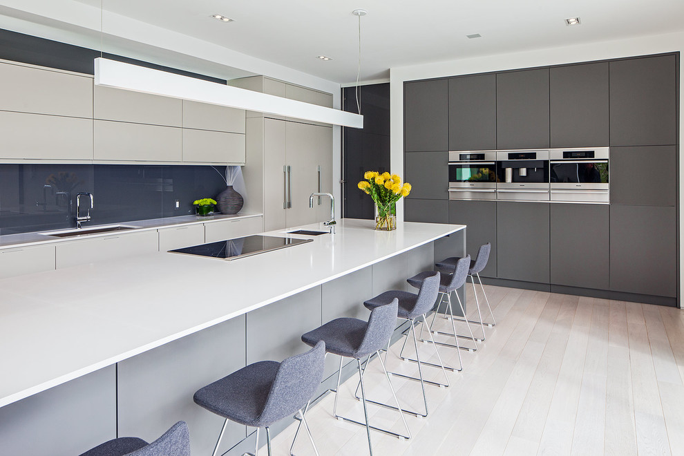 Zweizeilige Skandinavische Küche in grau-weiß mit Unterbauwaschbecken, flächenbündigen Schrankfronten, grauen Schränken, Küchenrückwand in Blau und Glasrückwand in Toronto