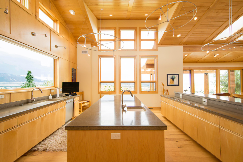 Bild på ett funkis kök, med en undermonterad diskho, släta luckor, skåp i ljust trä, rostfria vitvaror, ljust trägolv och flera köksöar