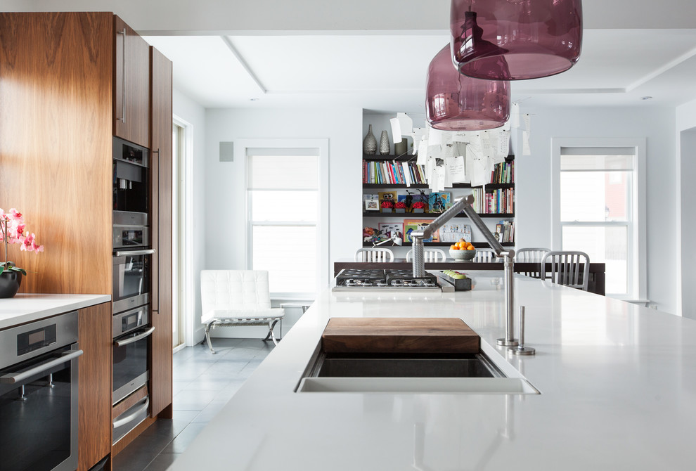 Moderne Wohnküche mit flächenbündigen Schrankfronten, hellbraunen Holzschränken und Küchengeräten aus Edelstahl in Sonstige