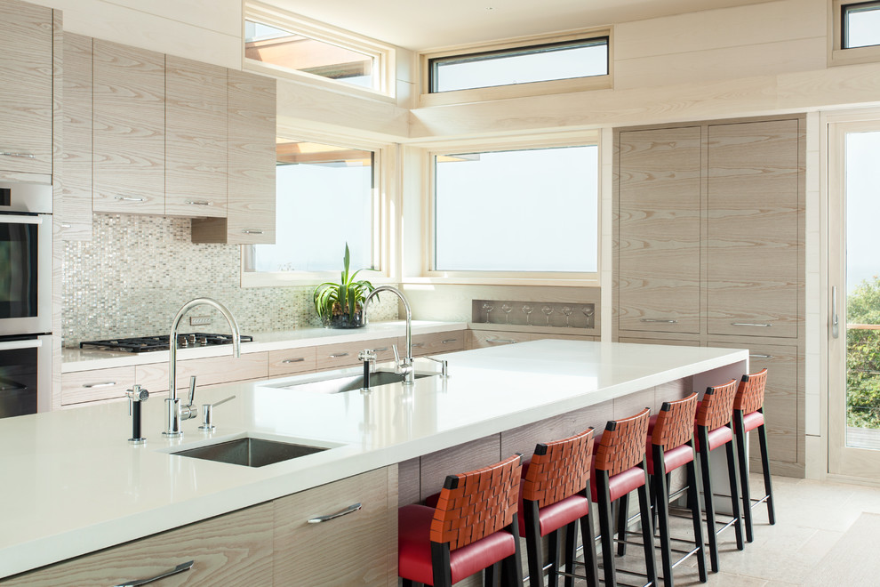 Große Moderne Wohnküche mit flächenbündigen Schrankfronten, hellen Holzschränken, Mineralwerkstoff-Arbeitsplatte, Küchenrückwand in Grau, Rückwand aus Mosaikfliesen, Küchengeräten aus Edelstahl, Keramikboden und Kücheninsel in Boston