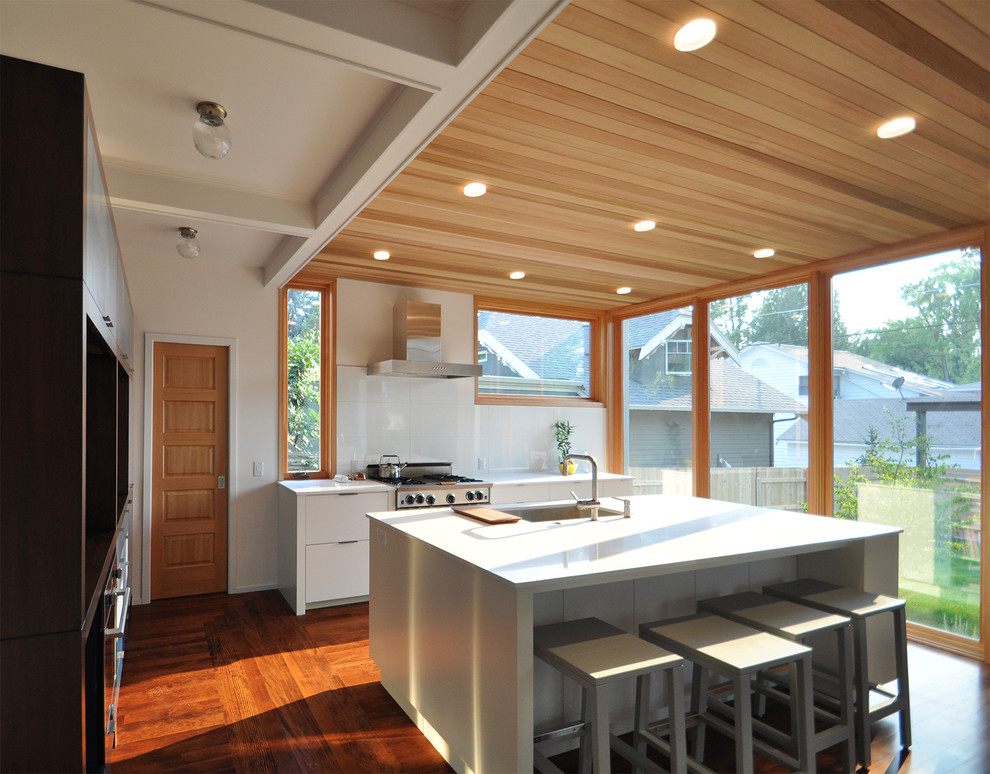 Eat-in kitchen - mid-sized contemporary l-shaped light wood floor eat-in kitchen idea in Boise with an undermount sink, flat-panel cabinets, white cabinets, solid surface countertops, stainless steel appliances and an island