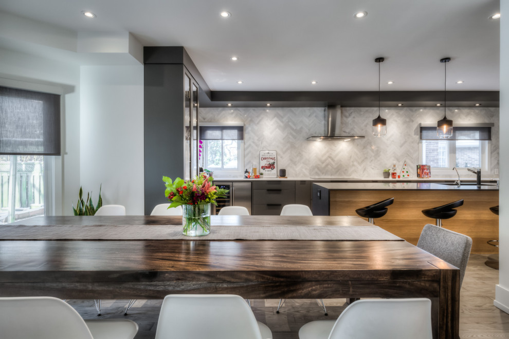 Eat-in kitchen - large modern galley medium tone wood floor and gray floor eat-in kitchen idea in Toronto with an undermount sink, flat-panel cabinets, gray cabinets, white backsplash, marble backsplash, stainless steel appliances, an island and black countertops