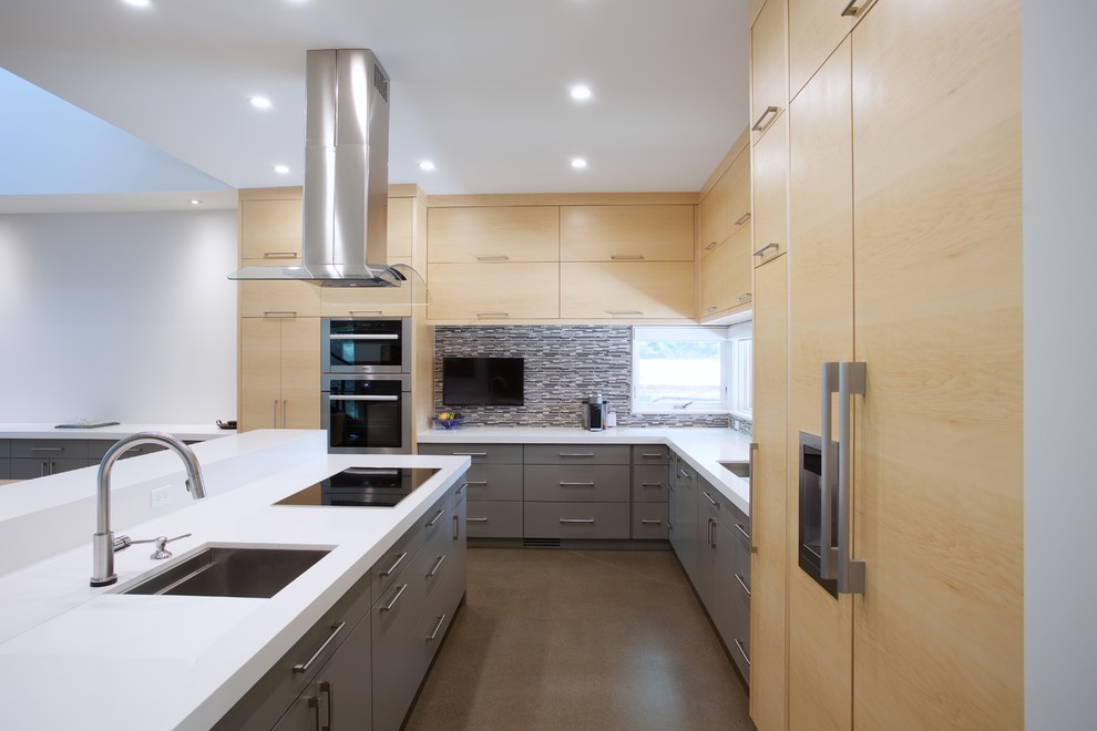 Large contemporary l-shaped kitchen/diner in Toronto with a built-in sink, flat-panel cabinets, light wood cabinets, multi-coloured splashback, mosaic tiled splashback, stainless steel appliances, concrete flooring and an island.