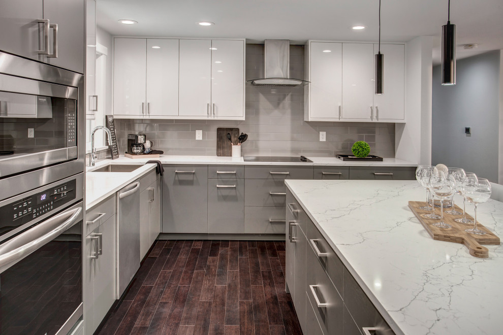 This is an example of a medium sized modern l-shaped open plan kitchen in Seattle with a submerged sink, flat-panel cabinets, white cabinets, quartz worktops, grey splashback, ceramic splashback, stainless steel appliances, dark hardwood flooring, an island, brown floors and white worktops.