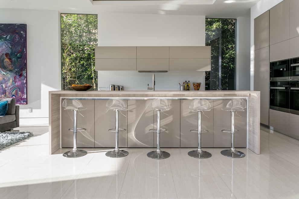 Example of a mid-sized minimalist l-shaped ceramic tile open concept kitchen design in Los Angeles with a double-bowl sink, flat-panel cabinets, beige cabinets, quartz countertops, white backsplash, stainless steel appliances and an island