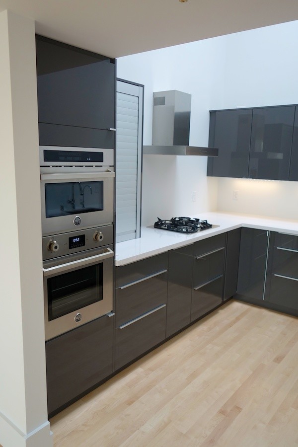 Пример оригинального дизайна: отдельная, п-образная кухня в стиле модернизм с врезной мойкой, плоскими фасадами, серыми фасадами, столешницей из кварцевого агломерата, белым фартуком и техникой из нержавеющей стали