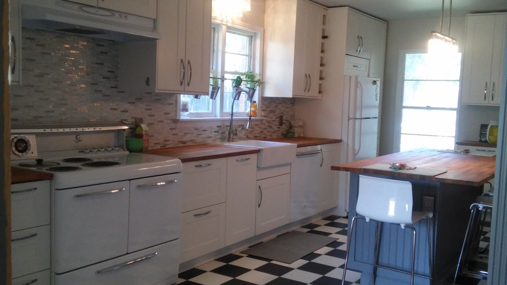 Mid-sized trendy l-shaped vinyl floor eat-in kitchen photo in San Francisco with a farmhouse sink, shaker cabinets, white cabinets, wood countertops, gray backsplash, mosaic tile backsplash, white appliances and an island