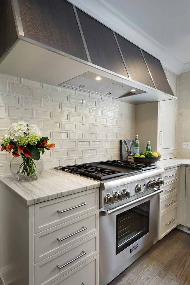 Foto på ett stort funkis vit kök, med luckor med infälld panel, vita skåp, bänkskiva i kvartsit, vitt stänkskydd, stänkskydd i cementkakel, rostfria vitvaror, ljust trägolv och en köksö