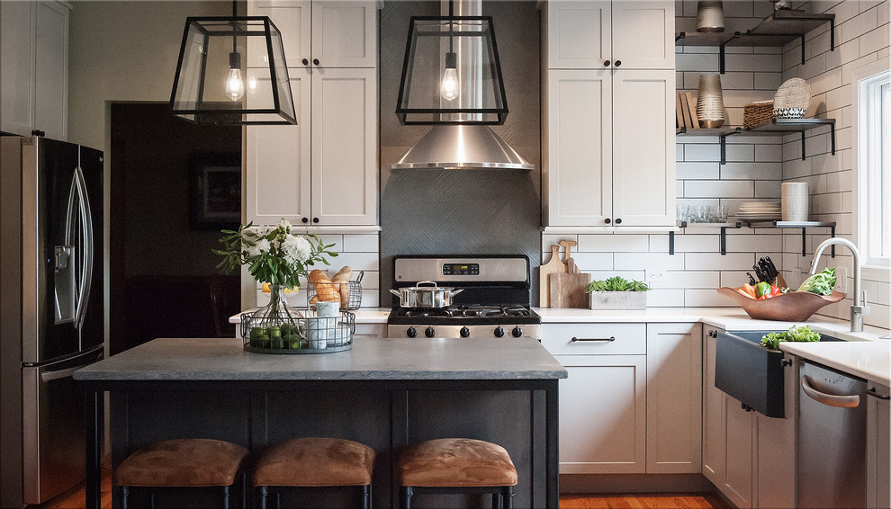 Inspiration for a mid-sized industrial u-shaped light wood floor and beige floor eat-in kitchen remodel in Chicago with a farmhouse sink, shaker cabinets, gray cabinets, quartz countertops, white backsplash, ceramic backsplash, stainless steel appliances, an island and gray countertops