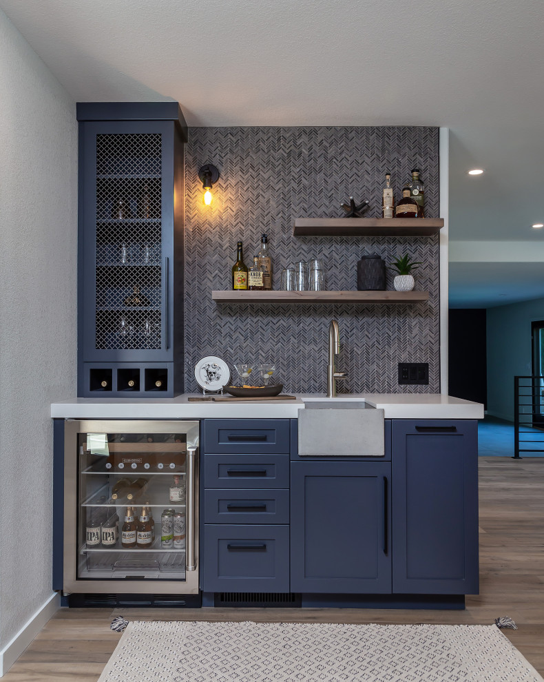 Inspiration for a large industrial l-shaped home bar in San Francisco with a submerged sink, shaker cabinets, black cabinets, granite worktops, stone slab splashback, laminate floors, brown floors and black worktops.