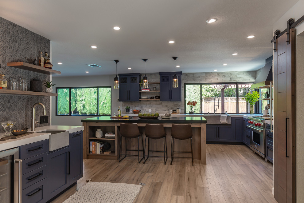 Example of a large urban l-shaped laminate floor and brown floor eat-in kitchen design in San Francisco with an undermount sink, shaker cabinets, black cabinets, granite countertops, stone slab backsplash, stainless steel appliances, an island and black countertops