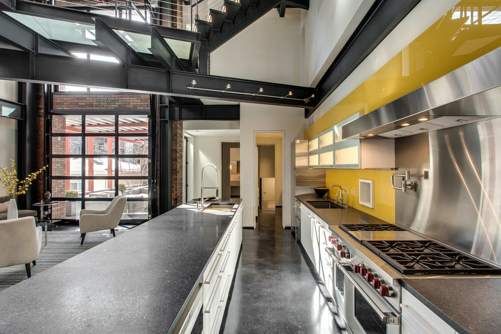 Стильный дизайн: параллельная кухня-гостиная в стиле лофт с накладной мойкой, белыми фасадами, техникой из нержавеющей стали, бетонным полом, островом, черным полом и черной столешницей - последний тренд