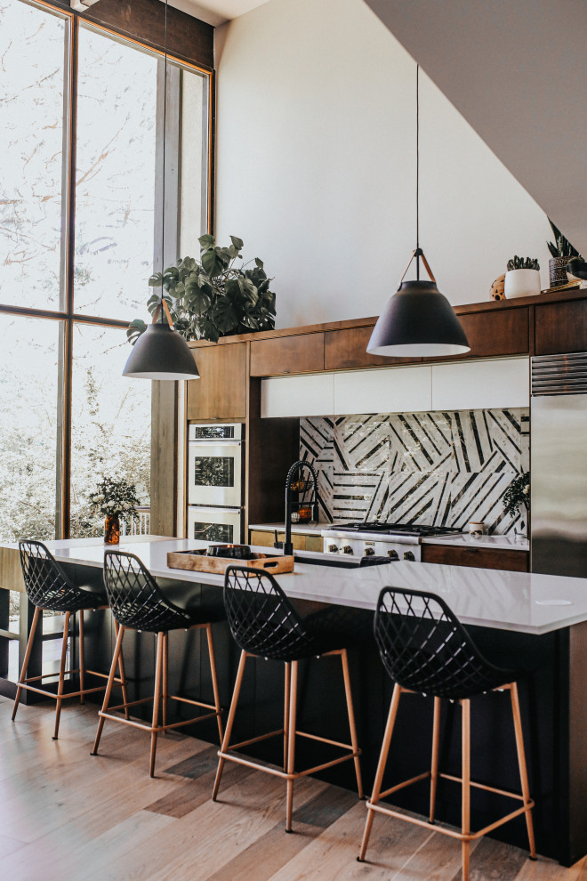 Zweizeilige Moderne Küche mit Unterbauwaschbecken, flächenbündigen Schrankfronten, dunklen Holzschränken, bunter Rückwand, Küchengeräten aus Edelstahl, hellem Holzboden, Kücheninsel, beigem Boden und weißer Arbeitsplatte in Seattle