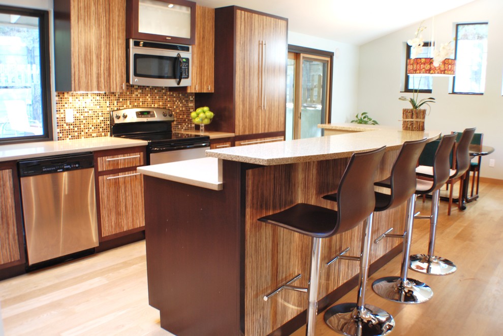Moderne Küche mit flächenbündigen Schrankfronten, hellbraunen Holzschränken, bunter Rückwand und Küchengeräten aus Edelstahl in Boise