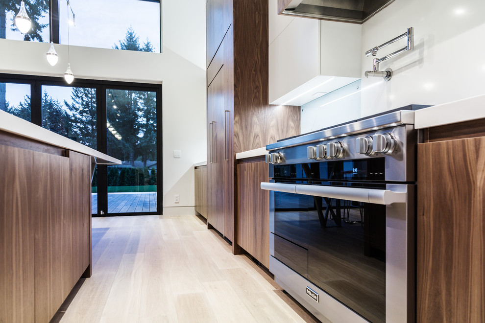 This is an example of a large modern single-wall kitchen/diner in Portland with a double-bowl sink, flat-panel cabinets, engineered stone countertops, white splashback, glass sheet splashback, integrated appliances, bamboo flooring, an island, beige floors and medium wood cabinets.