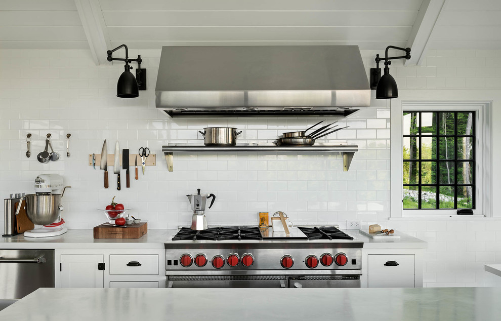 ニューヨークにあるカントリー風のおしゃれなキッチン (フラットパネル扉のキャビネット、白いキャビネット、白いキッチンパネル、サブウェイタイルのキッチンパネル、シルバーの調理設備) の写真