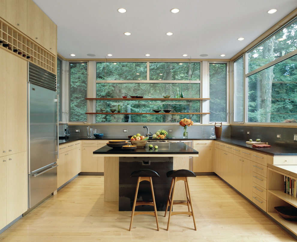 Cette photo montre une cuisine moderne en bois clair avec un placard à porte plane et un électroménager en acier inoxydable.